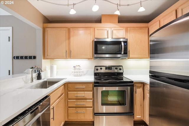 kitchen with track lighting, appliances with stainless steel finishes, light brown cabinetry, and sink