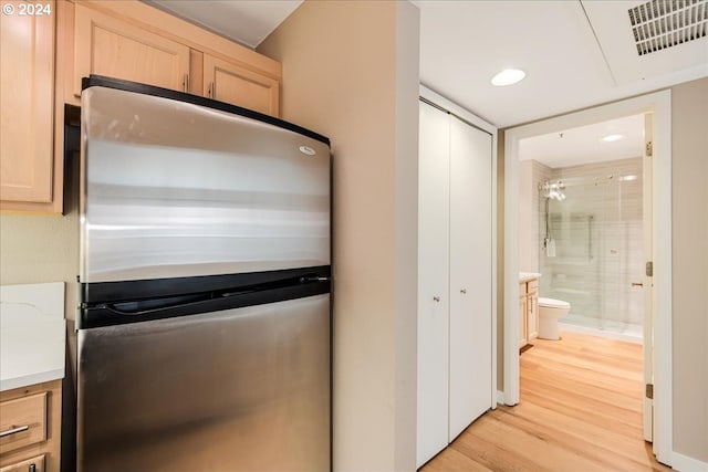 kitchen featuring light brown cabinets, light hardwood / wood-style floors, and stainless steel fridge