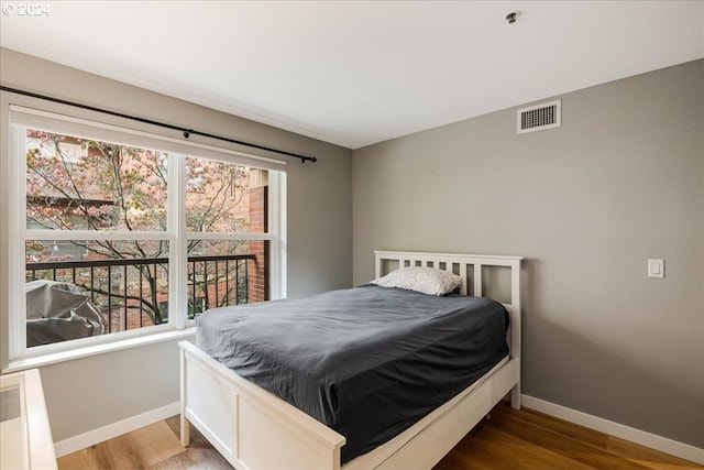 bedroom with hardwood / wood-style floors and multiple windows