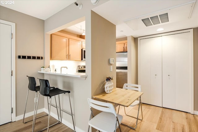 kitchen featuring light brown cabinetry, appliances with stainless steel finishes, and light hardwood / wood-style flooring