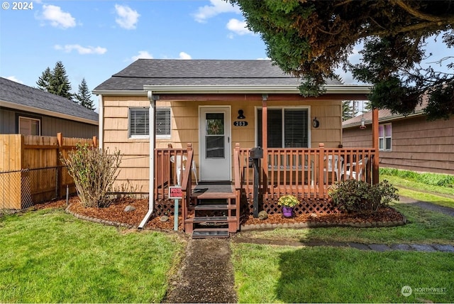 bungalow with a front lawn and a wooden deck