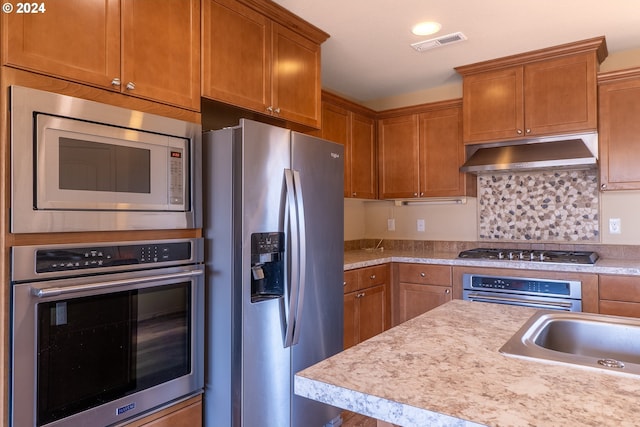 421 Little Lake Rd, Maupin, OR 97037 - kitchen with stainless steel appliances, under cabinet range hood, light countertops, tasteful backsplash, and brown cabinetry