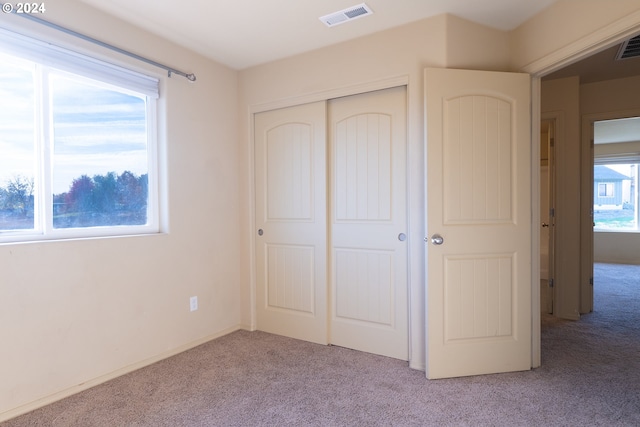 unfurnished bedroom featuring a closet and light colored carpet