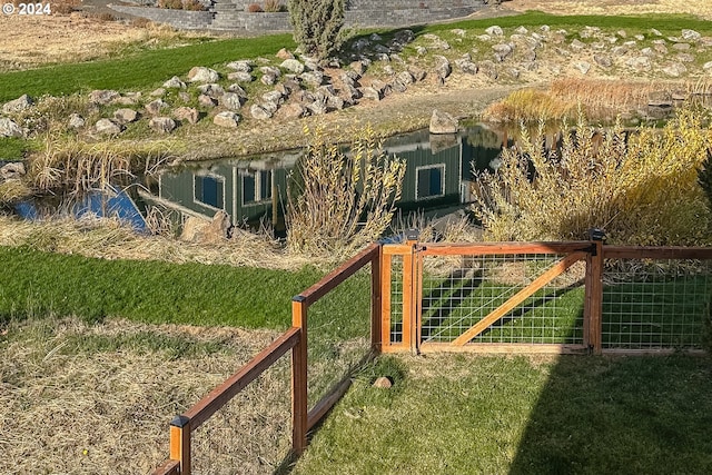 view of gate with a yard and a water view