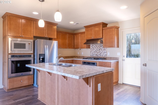 kitchen featuring a center island with sink, pendant lighting, dark hardwood / wood-style floors, and appliances with stainless steel finishes