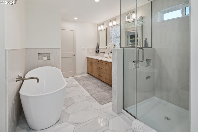 bathroom with vanity, independent shower and bath, and tile walls