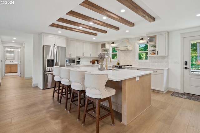 kitchen featuring light hardwood / wood-style floors, a wealth of natural light, stainless steel appliances, and a center island with sink