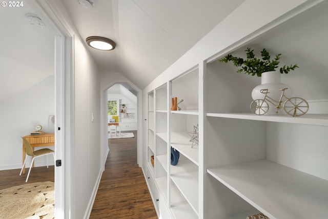 corridor with baseboards, wood finished floors, and vaulted ceiling