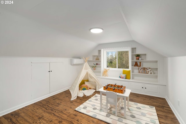 recreation room with dark wood-type flooring, built in shelves, baseboards, and vaulted ceiling