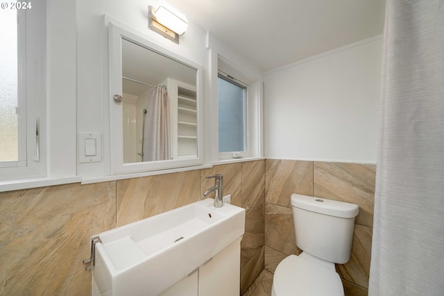 bathroom featuring tile walls, toilet, and a sink