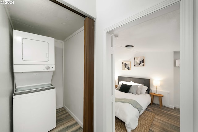 clothes washing area with laundry area, wood finished floors, baseboards, and stacked washing maching and dryer