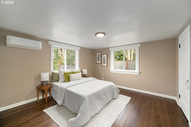 bedroom featuring a wall unit AC, multiple windows, dark wood-style floors, and baseboards