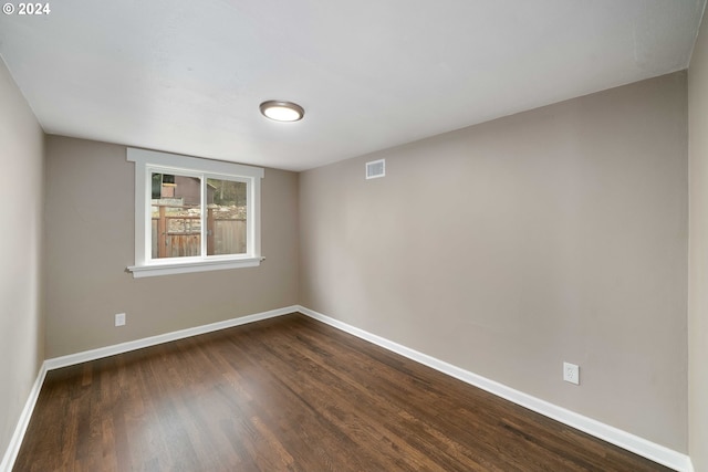 spare room with visible vents, baseboards, and dark wood finished floors