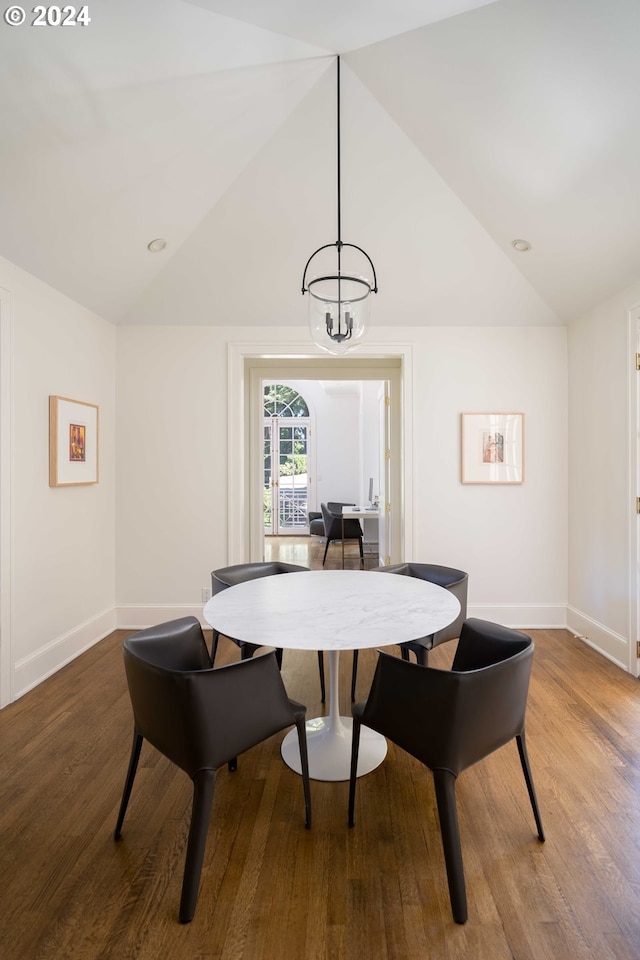 dining room featuring wood-type flooring, lofted ceiling, and an inviting chandelier