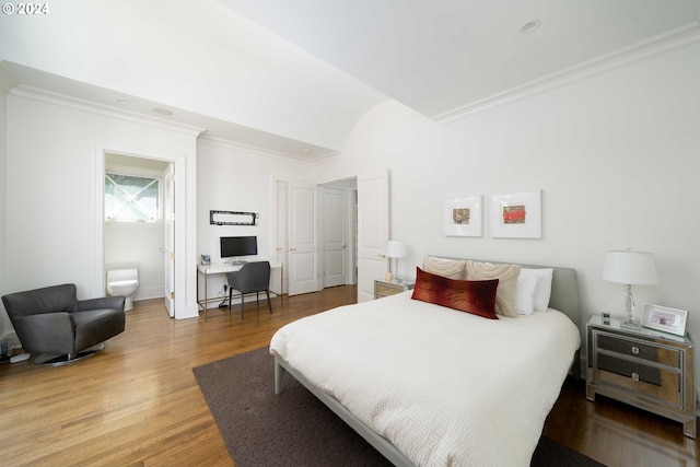 bedroom with hardwood / wood-style flooring, crown molding, and connected bathroom