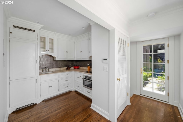 kitchen featuring sink, tasteful backsplash, dark hardwood / wood-style flooring, oven, and white cabinets