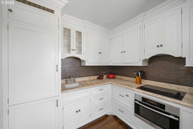 kitchen featuring oven, sink, decorative backsplash, black cooktop, and white cabinetry