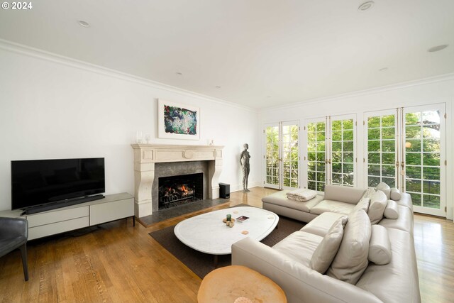 living room with a fireplace, french doors, ornamental molding, and wood-type flooring