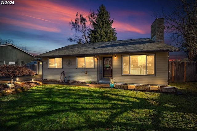 back house at dusk featuring a yard