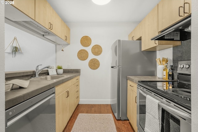 kitchen with sink, light hardwood / wood-style flooring, ventilation hood, appliances with stainless steel finishes, and light brown cabinetry