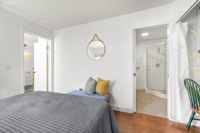 bedroom with ensuite bath and hardwood / wood-style floors