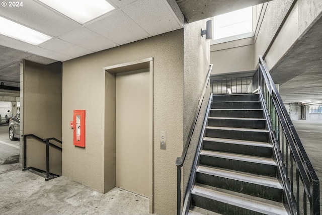 stairs featuring elevator and concrete floors