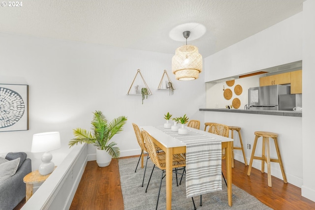 dining space with a textured ceiling and dark hardwood / wood-style floors