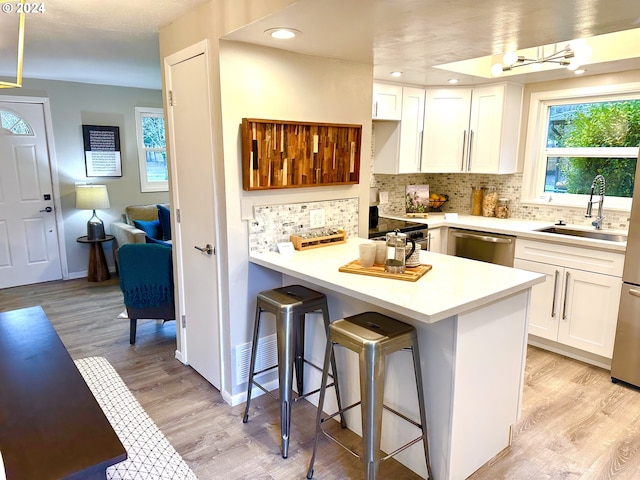 kitchen featuring white cabinetry, sink, appliances with stainless steel finishes, and a breakfast bar area