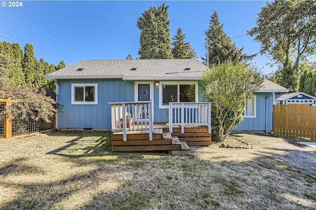 view of front facade with a wooden deck and a front yard