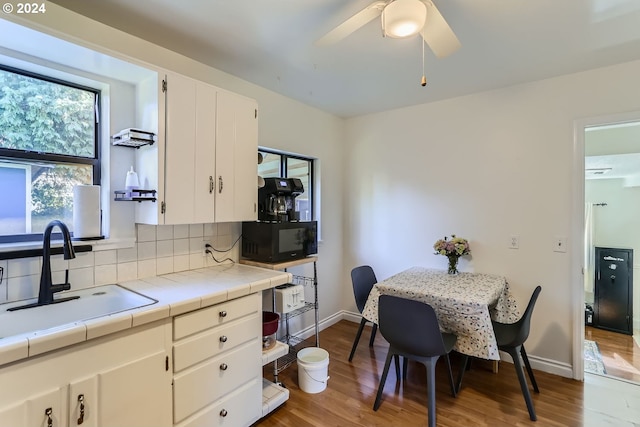 kitchen featuring sink, white cabinetry, tile counters, hardwood / wood-style floors, and decorative backsplash