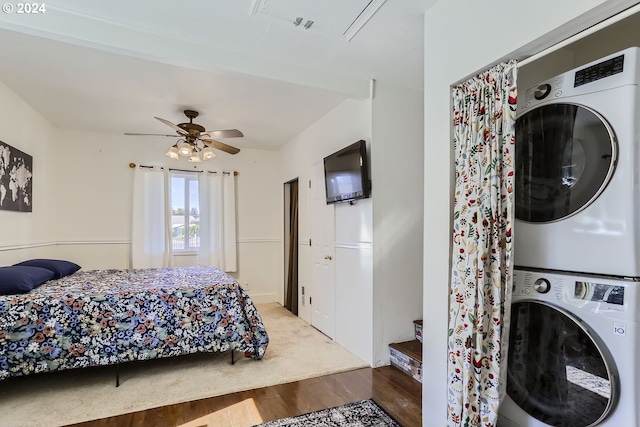 bedroom featuring ceiling fan, stacked washer / dryer, and hardwood / wood-style flooring