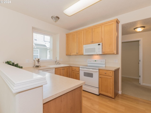 kitchen featuring white appliances, kitchen peninsula, sink, light brown cabinetry, and light colored carpet