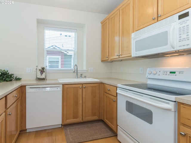 kitchen with white appliances, sink, and light hardwood / wood-style floors