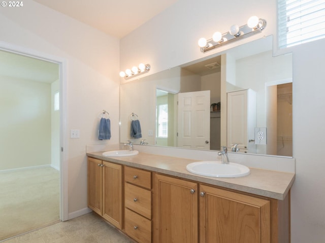 bathroom featuring tile floors, a healthy amount of sunlight, and double sink vanity