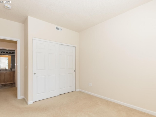 unfurnished bedroom featuring a closet and light colored carpet