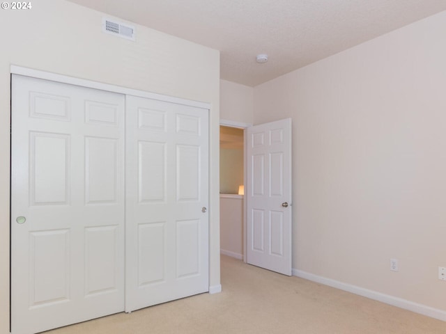 unfurnished bedroom featuring light carpet and a closet