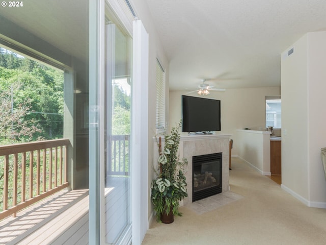 living room featuring ceiling fan, a healthy amount of sunlight, a fireplace, and light colored carpet