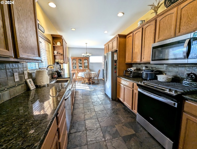 kitchen with appliances with stainless steel finishes, a healthy amount of sunlight, decorative backsplash, and sink