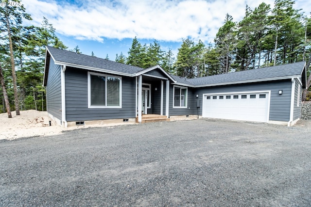 view of front facade featuring a garage, a shingled roof, and gravel driveway