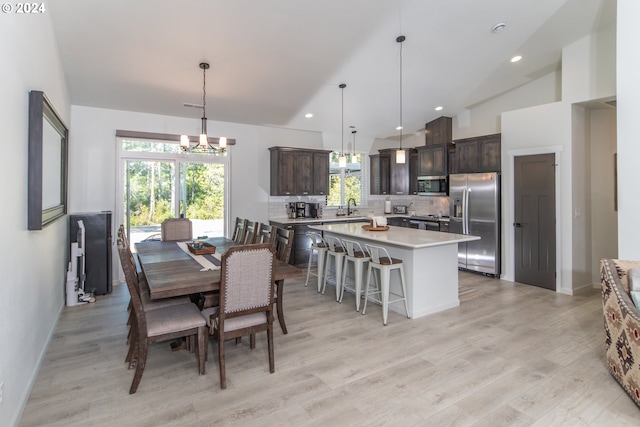 dining space with light wood finished floors, a chandelier, high vaulted ceiling, and recessed lighting