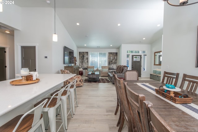 dining space featuring high vaulted ceiling, light wood-style flooring, and recessed lighting