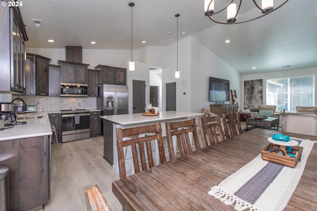 kitchen featuring stainless steel appliances, open floor plan, light countertops, and a kitchen island