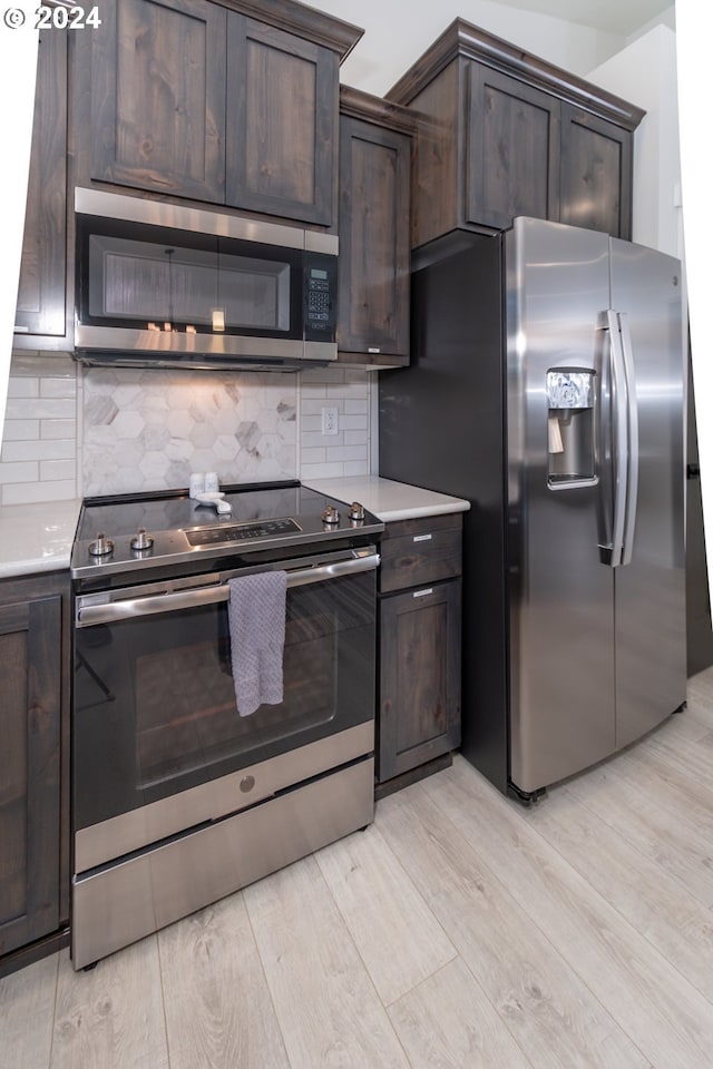 kitchen with stainless steel appliances, backsplash, light countertops, and dark brown cabinetry