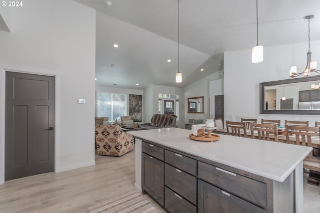 kitchen featuring decorative light fixtures, lofted ceiling, light countertops, open floor plan, and a kitchen island