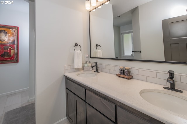 full bathroom with double vanity, a sink, and baseboards