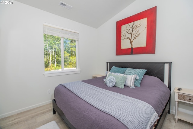 bedroom with vaulted ceiling, light wood finished floors, visible vents, and baseboards