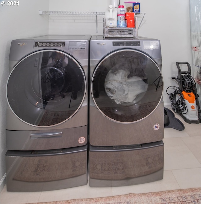 clothes washing area featuring laundry area, washing machine and dryer, and tile patterned floors