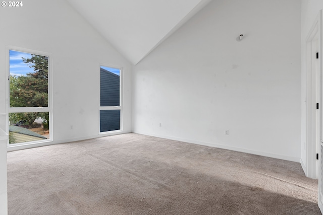 spare room with carpet flooring and high vaulted ceiling