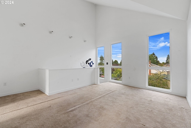 unfurnished living room with high vaulted ceiling and carpet flooring