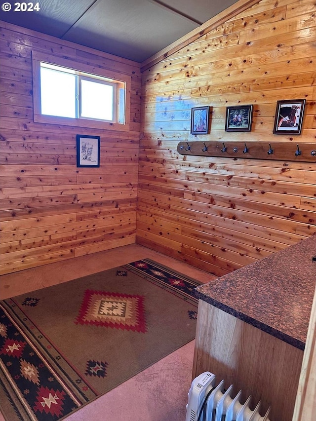 living area with carpet flooring, radiator heating unit, and wood walls